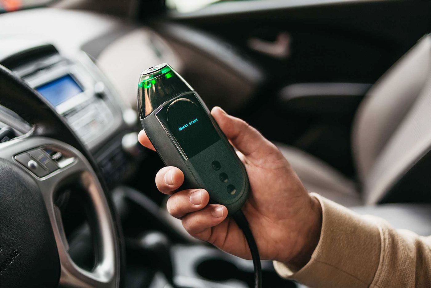 person holding an ignition interlock device unit in a vehicle